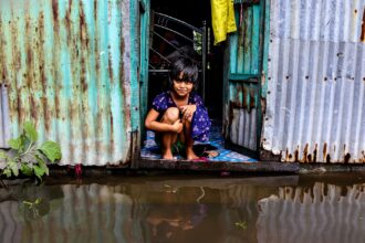 Children walking to damaged school building after climate disaster, symbolizing educational disruption