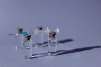 Medical researcher working with vaccine vials in laboratory setting for Lassa fever vaccine development
