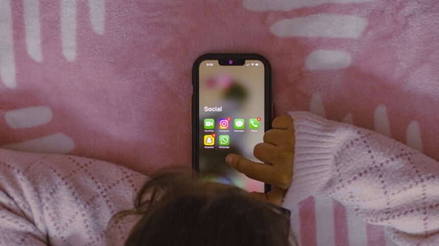 Parent distracted by phone while teenager sits nearby, illustrating parental screen time impact on adolescent attachment