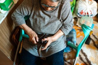 Adult child supporting aging parent during healthcare appointment, representing sandwich generation caregiving