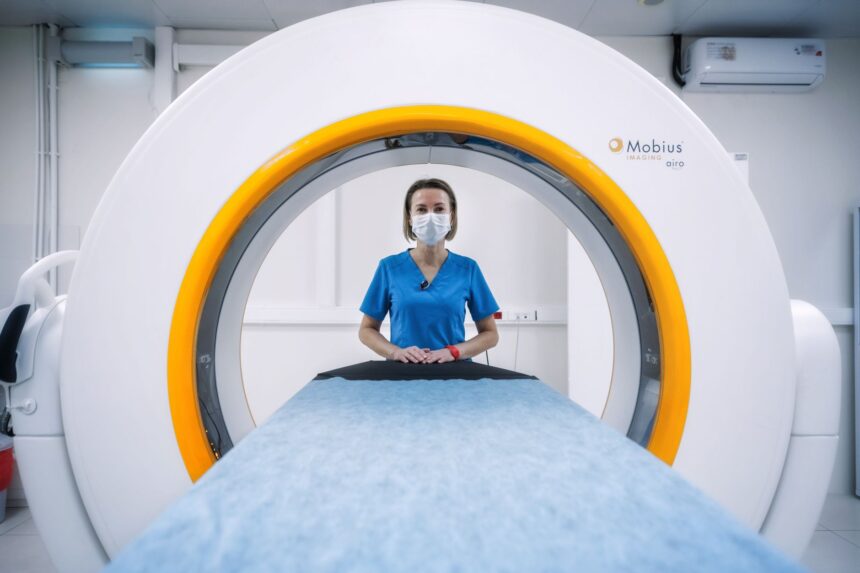 Child using miniature toy MRI scanner with stuffed animal during medical preparation session