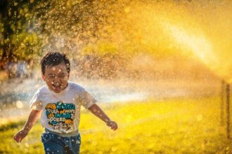 Child drinking water in summer heat; cooling strategies for paediatric heat illness prevention