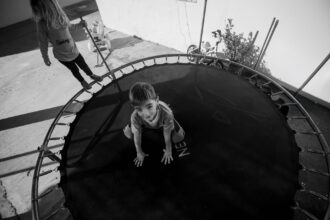 Child on trampoline with safety netting and protective padding