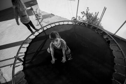Child on trampoline with safety netting and protective padding
