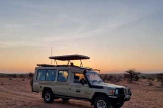 Safari 4x4 vehicle silhouetted against an African sunset